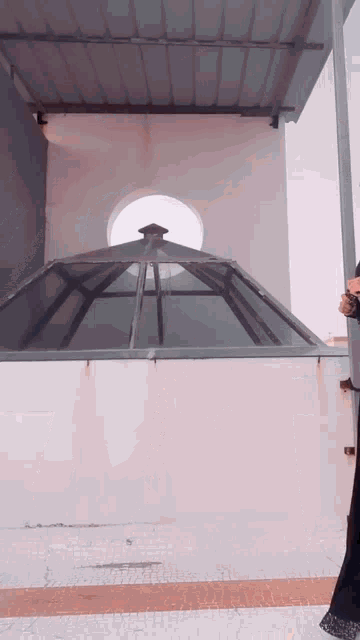 a woman is standing in front of a building with a roof that is open