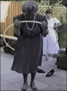 an elderly woman is playing with a hula hoop on the sidewalk ..