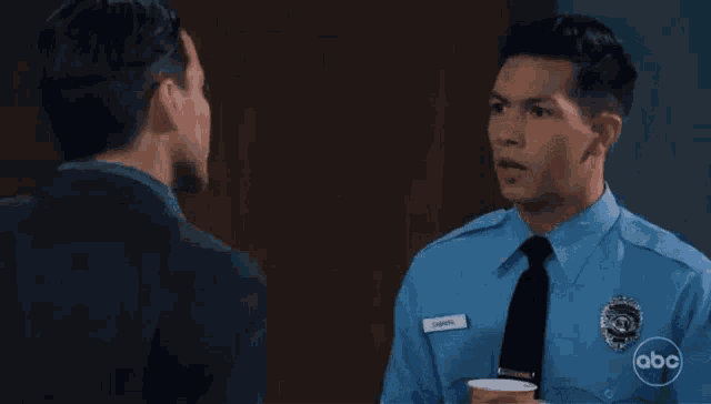 a man in a suit is talking to a police officer in a blue uniform .