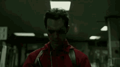 a group of men in red jackets are holding guns in a hallway .