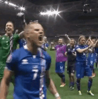 a group of soccer players in blue uniforms are celebrating on a field .