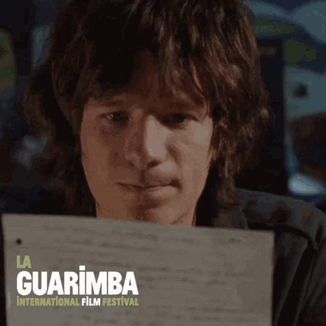 a man is looking at a piece of paper with la guarimba international film festival written on the bottom