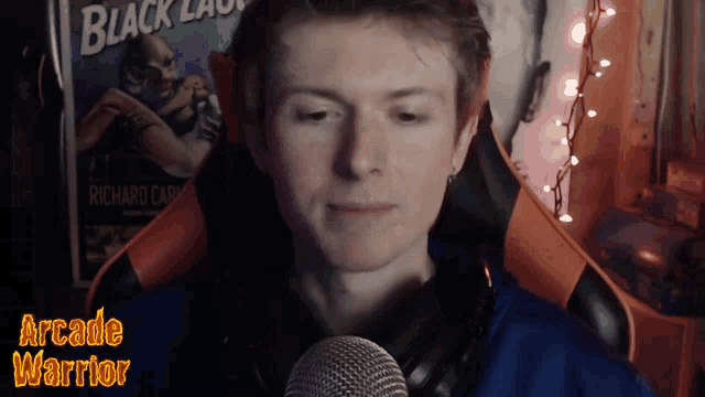 a man sitting in front of a microphone with the words arcade warrior written below him