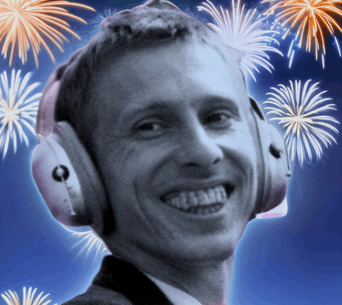 a man wearing headphones smiles with fireworks in the background