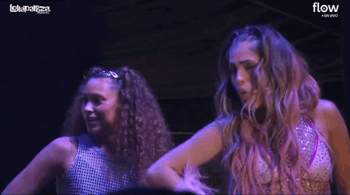 two women are dancing in front of a sign that says flow on it