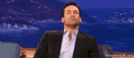 a man in a suit and white shirt is sitting in front of a blue background .