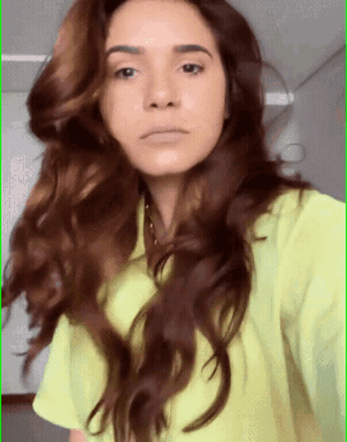 a woman with long brown hair is wearing a bright yellow shirt