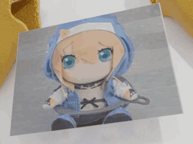 a picture of a stuffed doll with green eyes and a blue hoodie