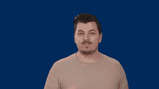 a man with a beard wearing a tan sweater