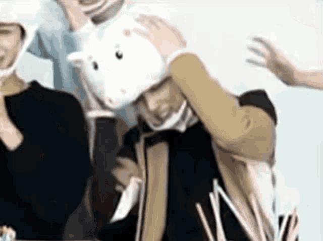 a man wearing a piggy bank hat is sitting in a crowd of people .