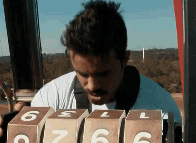 a man in a white shirt is playing a game with numbers on the boxes