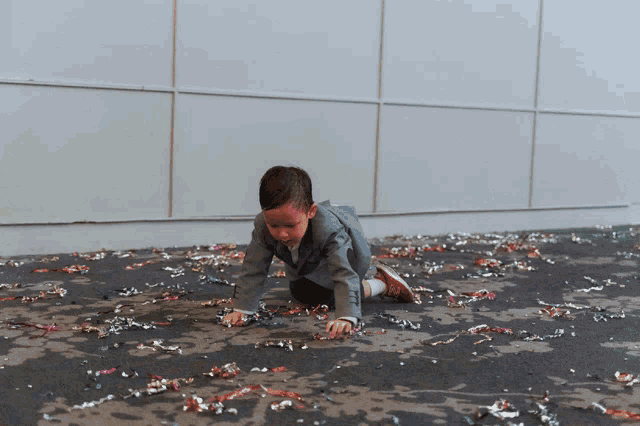 a young boy in a suit is crawling on a messy floor