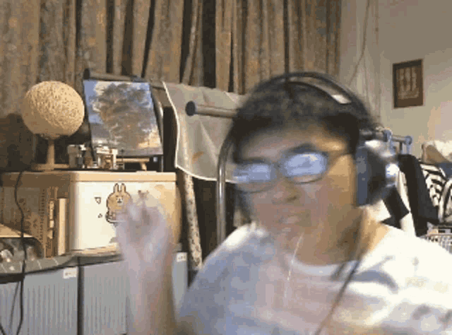 a man wearing headphones and glasses stands in front of a white box with a rabbit on it