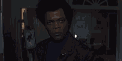 a man in a suit is standing in a dark room with the words `` no '' written on the wall .