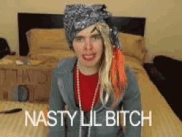 a woman with a bandana on her head is sitting on a bed with the words nasty lil bitch below her