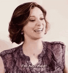 a woman in a purple shirt is smiling and saying `` i 'm terrified ! ''