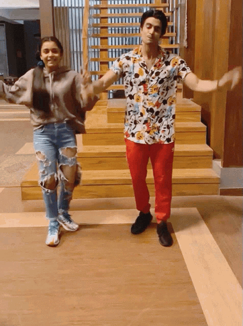 a man and a woman are dancing on a wooden floor in front of stairs