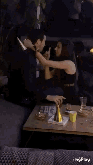 a man and a woman are sitting at a table with a newspaper and a party hat on it