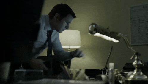 a man in a suit and tie is sitting at a desk in front of a lamp with the word one on it