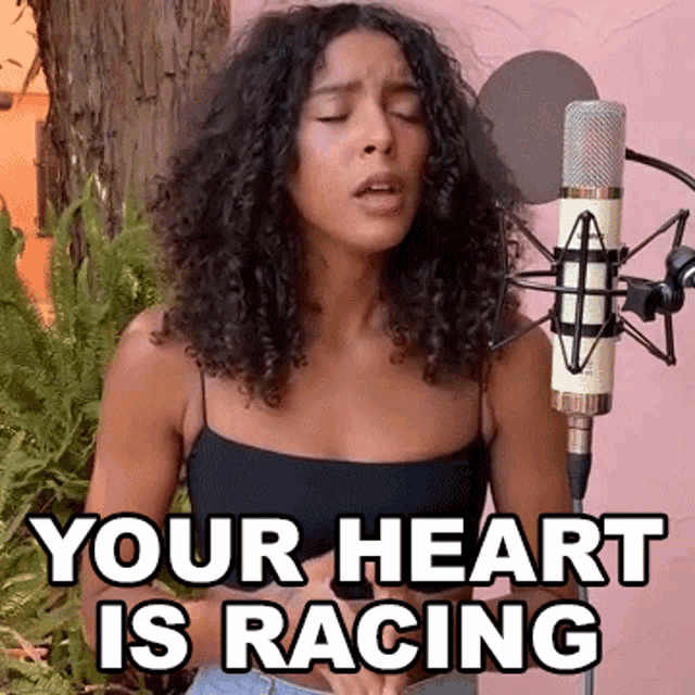 a woman is singing into a microphone with the words `` your heart is racing '' written on the bottom .