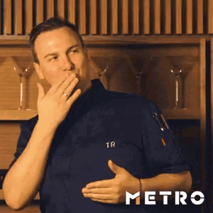 a man in a chef 's uniform is covering his mouth with his hand ..