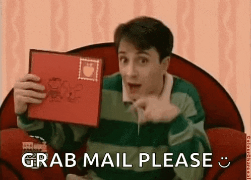 a man is sitting in a chair holding a book and pointing at it with the words grab mail please .