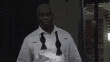a man wearing a white shirt and a black bow tie is standing in a dark room .