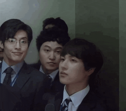 a group of young men in suits and ties are standing in a room