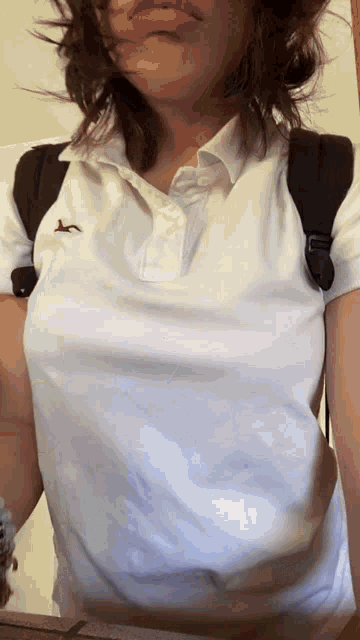 a girl wearing a white hollister polo shirt with a black backpack