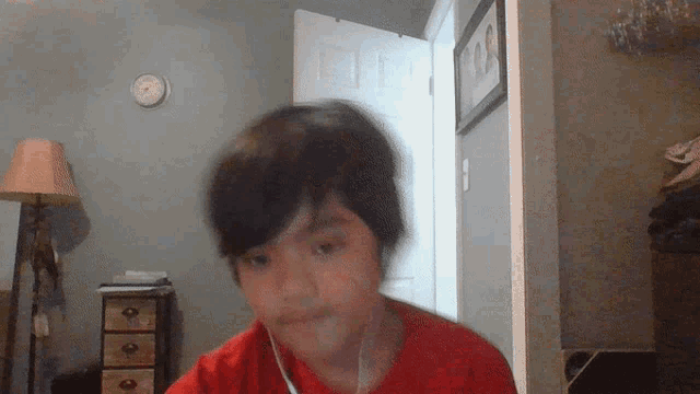 a young boy in a red shirt is looking at the camera
