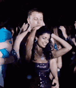 a woman in a purple dress is dancing in a crowd