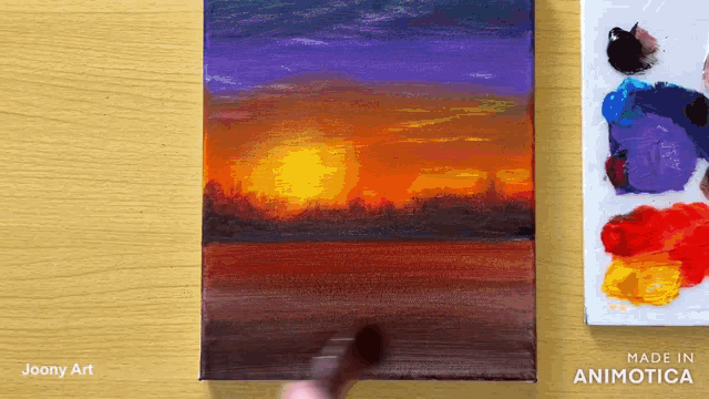 a person is painting a sunset on a canvas