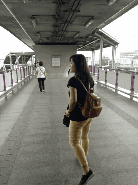 a woman walking across a bridge with a sign that says ' bangkok ' on it