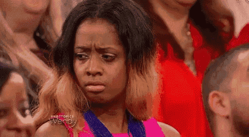 a woman is making a funny face while sitting in a crowd .