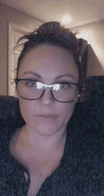 a woman wearing glasses looks at the camera