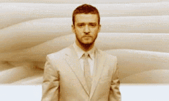 a man in a suit and tie is standing in front of a wall