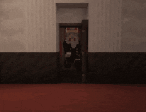 a very dark room with a red carpet and a door that is open