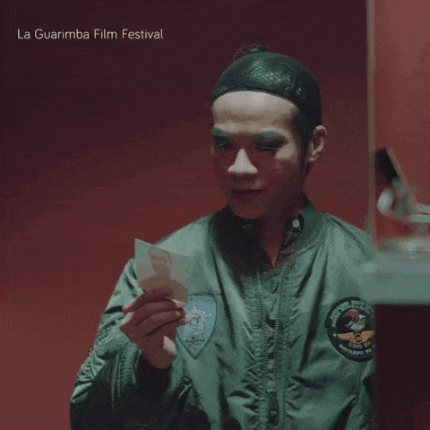 a man in a green jacket holds a piece of paper in his hand