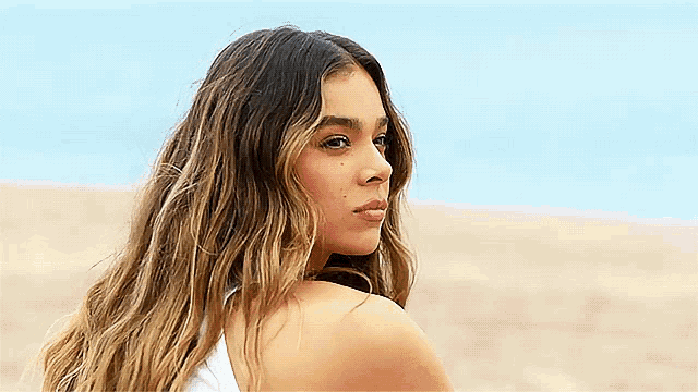 a woman with long hair is standing on a beach