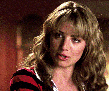 a woman with blonde hair and bangs is wearing a red and black striped sweater