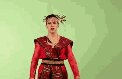 a woman in a red dress and headband is standing in front of a green background .