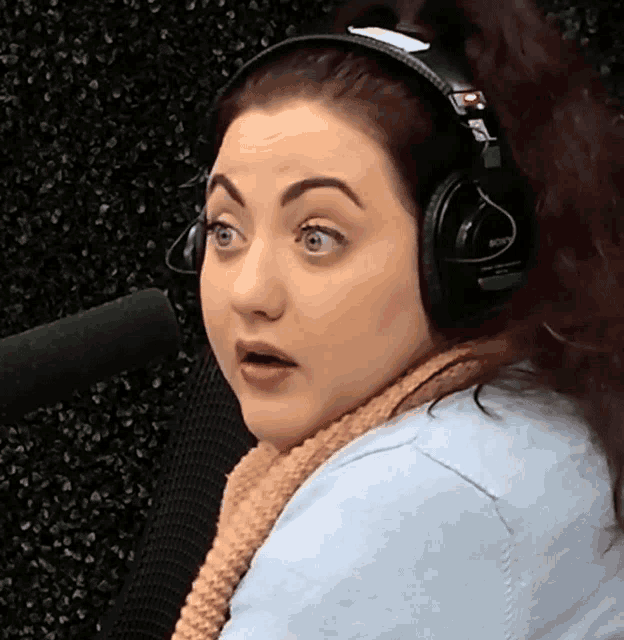 a woman wearing headphones and a scarf looks at the camera