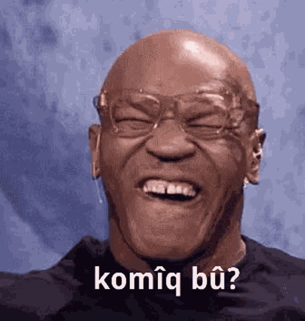 a bald man wearing glasses is making a funny face and laughing .
