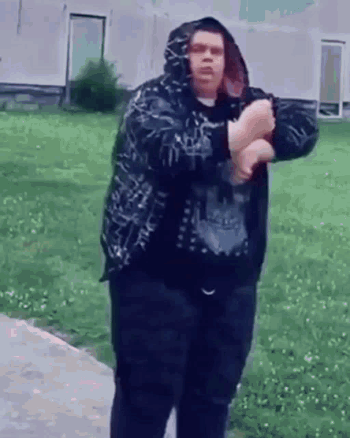 a man in a hoodie is standing on a sidewalk holding a gun .