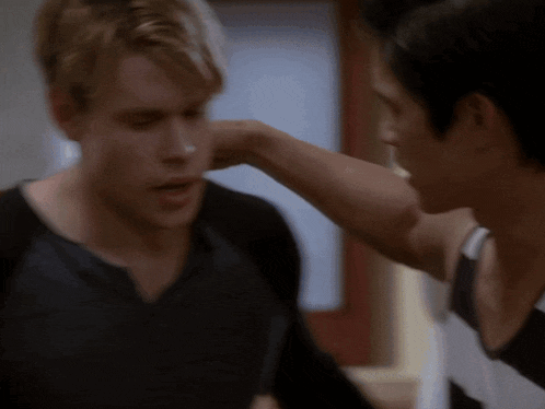 a man is putting his hand on another man 's ear .