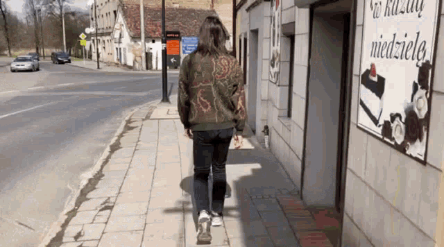 a woman is walking down a sidewalk in front of a building with a sign on it that says ' w kasie '