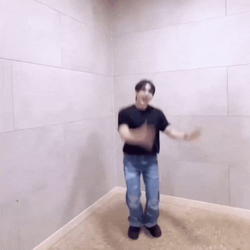 a man wearing a mask is dancing in a room with a white wall .