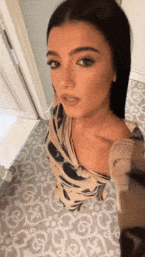 a woman taking a selfie in a bathroom with a patterned floor