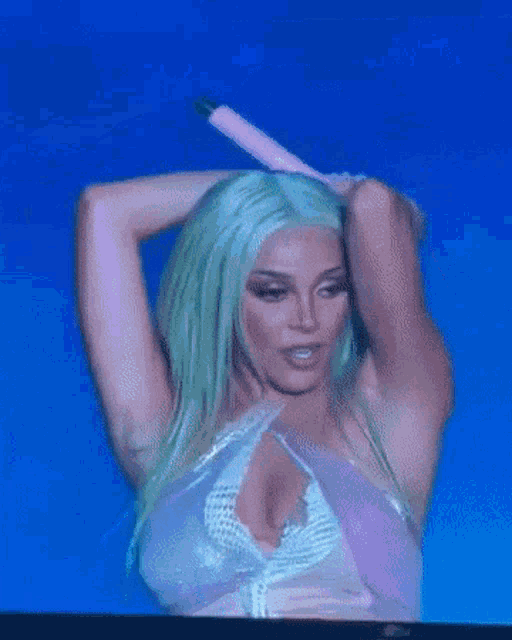 a woman with green hair is holding a pink microphone behind her head