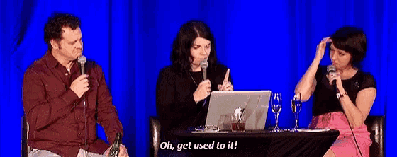 a man and two women are sitting at a table with a laptop and glasses and one of them is saying " oh get used to it